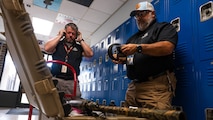 A photo of two men in a hallway equipping hearing protection gear.