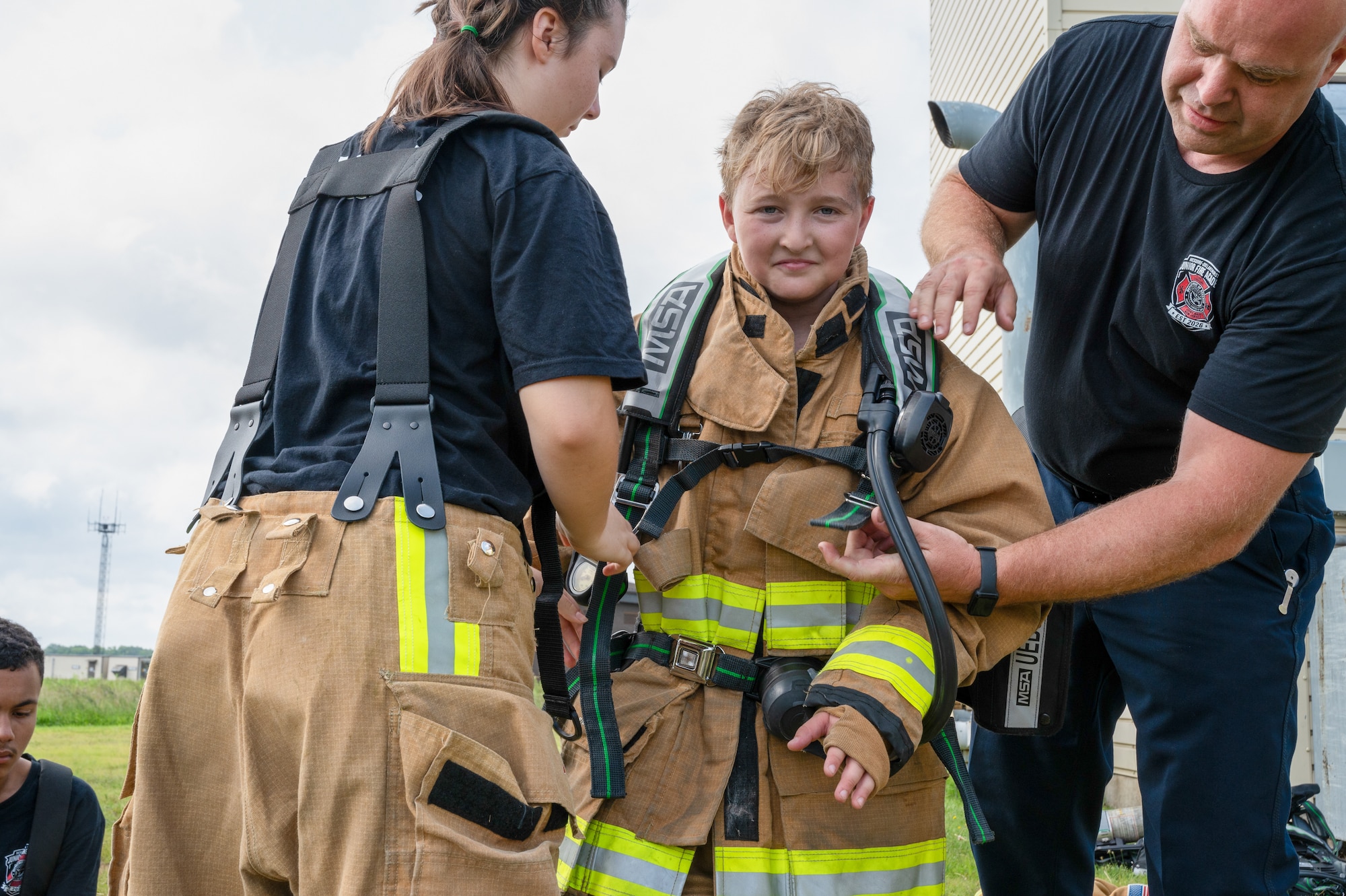 Members of the 87th Civil Engineer Squadron fire and emergency services assist a junior fire academy recruit with putting on the self-contained breathing apparatus at Joint Base McGuire-Dix-Lakehurst, N.J., July 29, 2026.