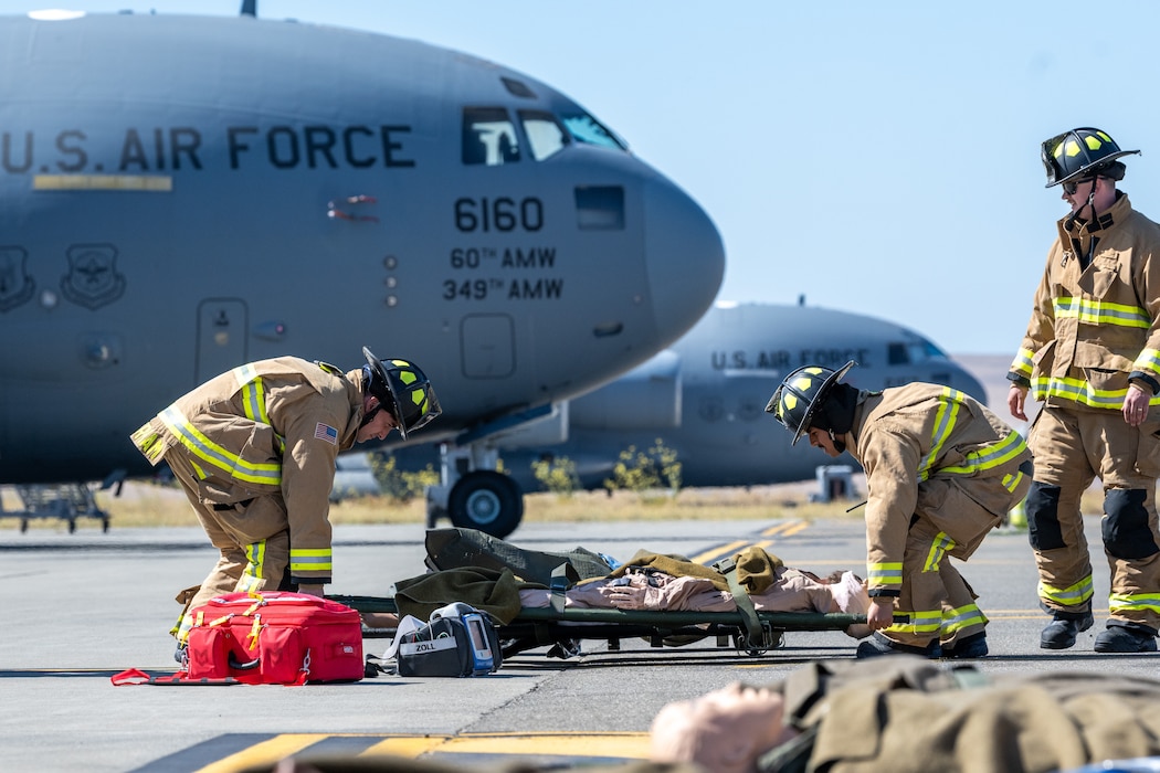 Firefighters transport simulated casualty on flight line.