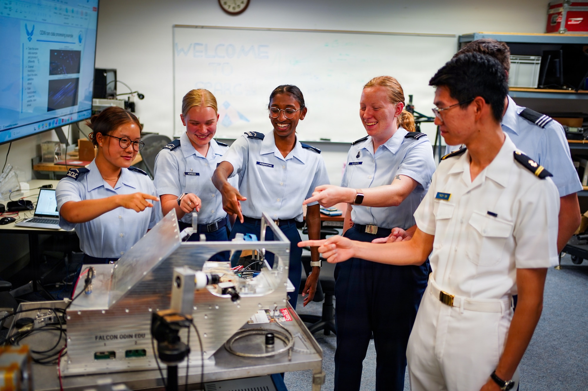 Student cadets standing around pointing at device