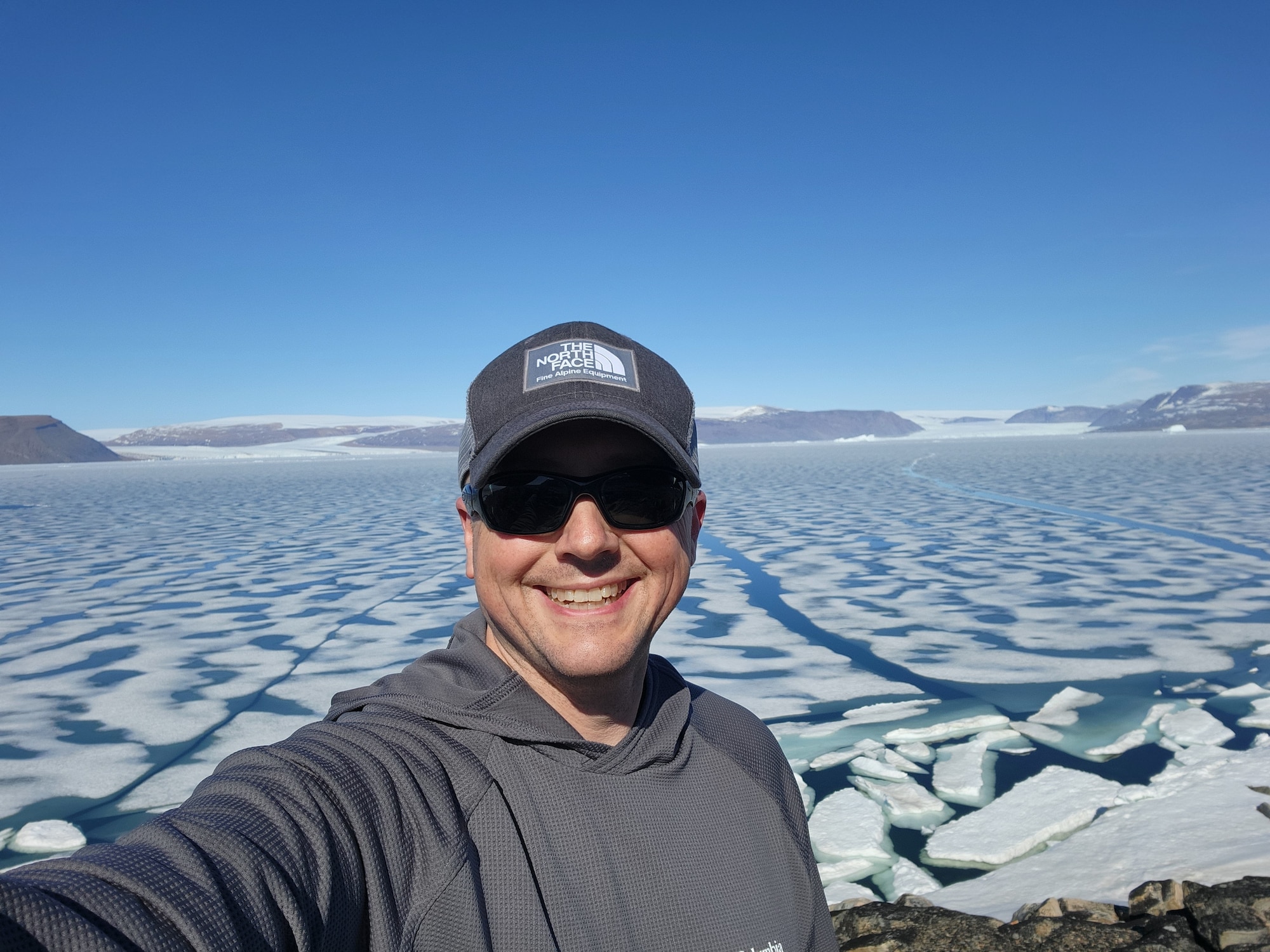 A service member snaps a photo of himself with the Arctic water melting behind him.
