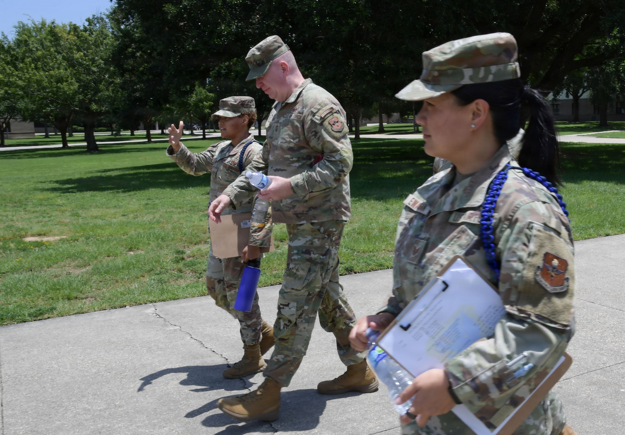 Three people wearing U.S. Air Force uniform speaks to each other while walking outside.