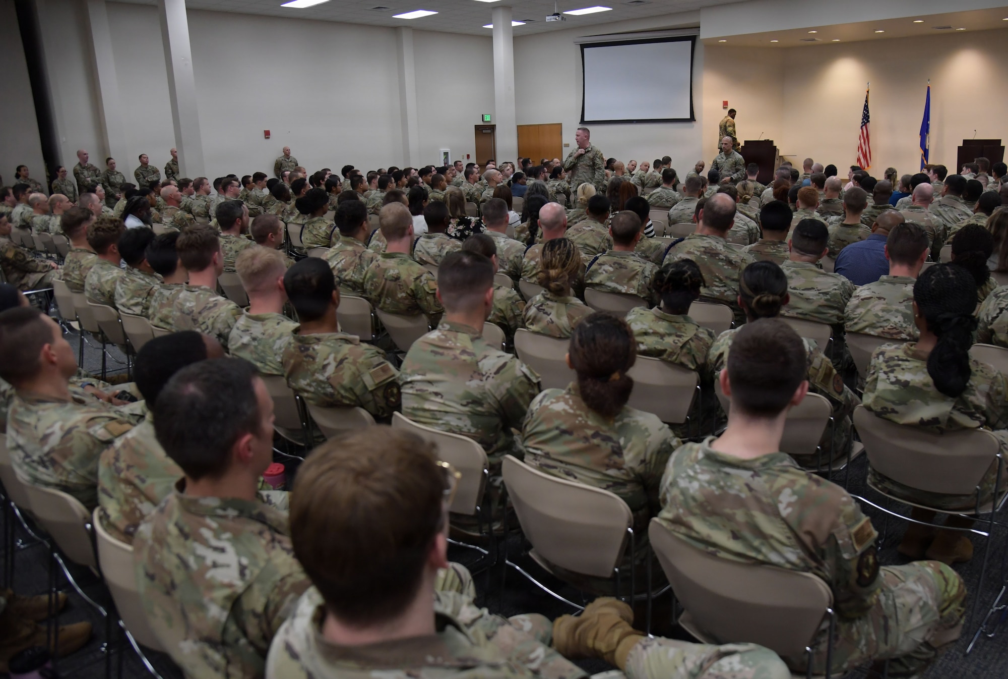 A man in a U.S. Air Force uniform speaks to a crowd of Airmen.