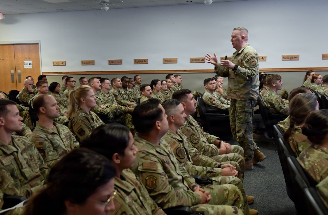 A man in a U.S. Air Force uniform speaks to a crowd of Airmen.