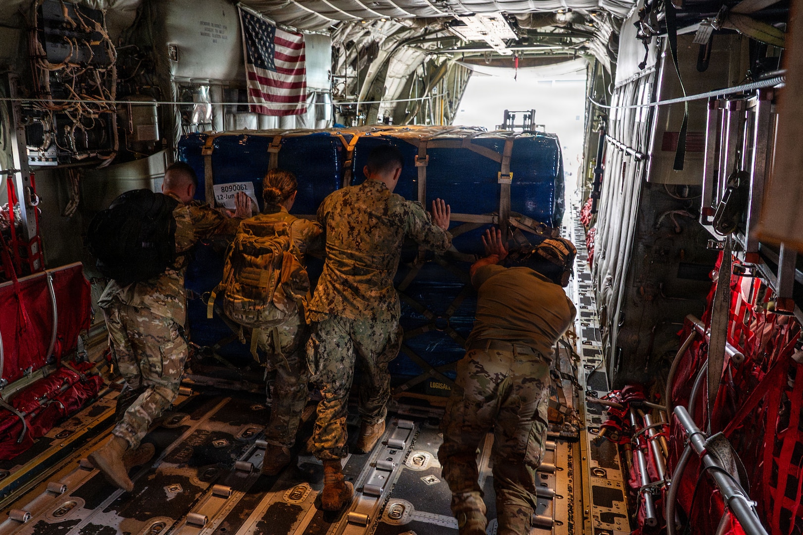 A group of people pushing cargo out of an aircraft