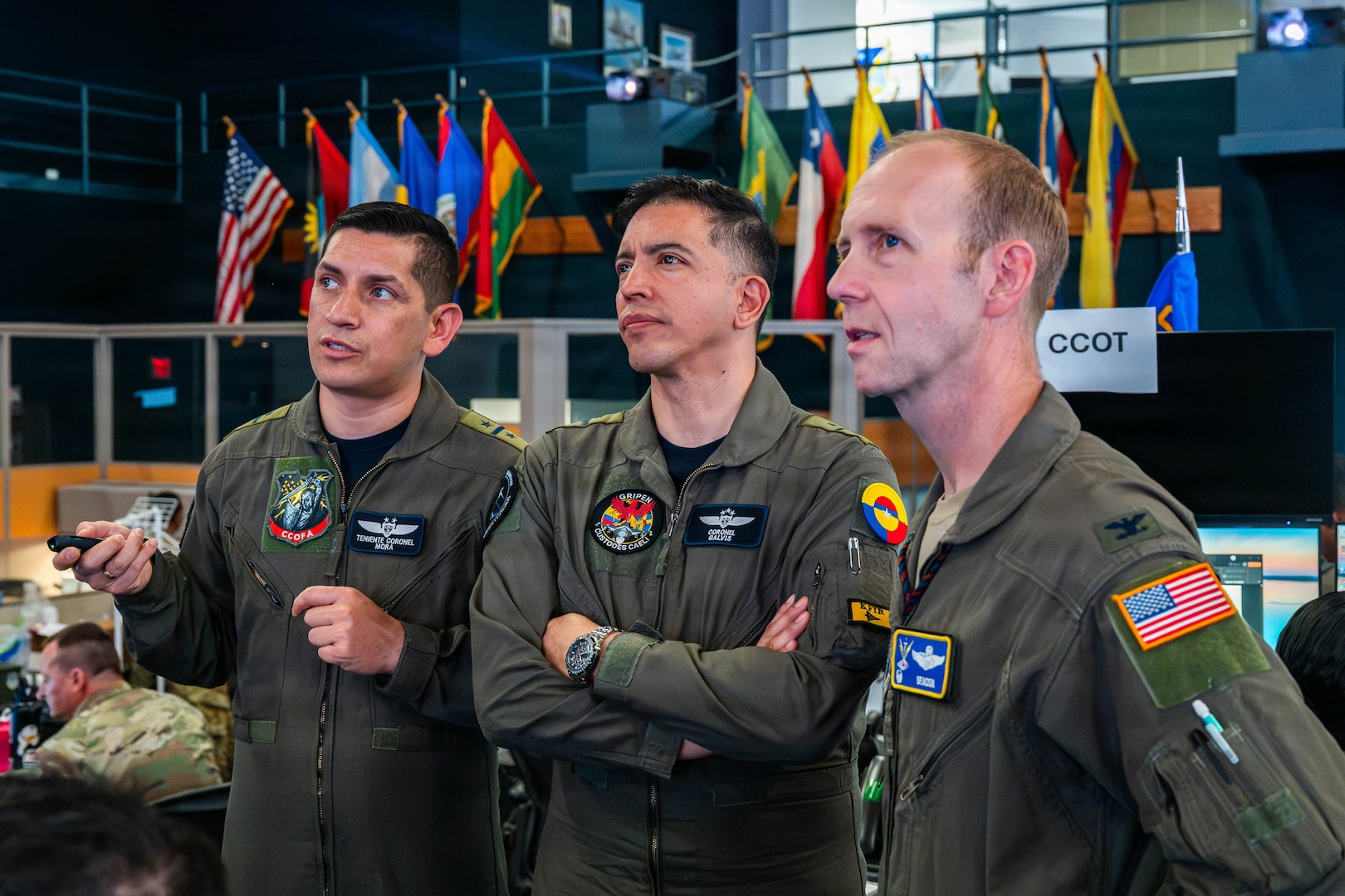 Colombian Aerospace Force Lt. Col. Juan Francisco Mora Moreno, left, provides an operational status update to Colombian Aerospace Force Col. Andrés Galvis Espejo, Deputy Combined Force Air Component Commander for PANAMAX 2026, center, and U.S. Air Force Col. Jonathan Grayson, 612th Air Operations Center commander, right, in the Combined Air Operations Center at Davis-Monthan Air Force Base, Arizona, Aug. 10, 2026.