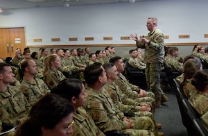 A man in a U.S. Air Force uniform speaks to a crowd of Airmen.