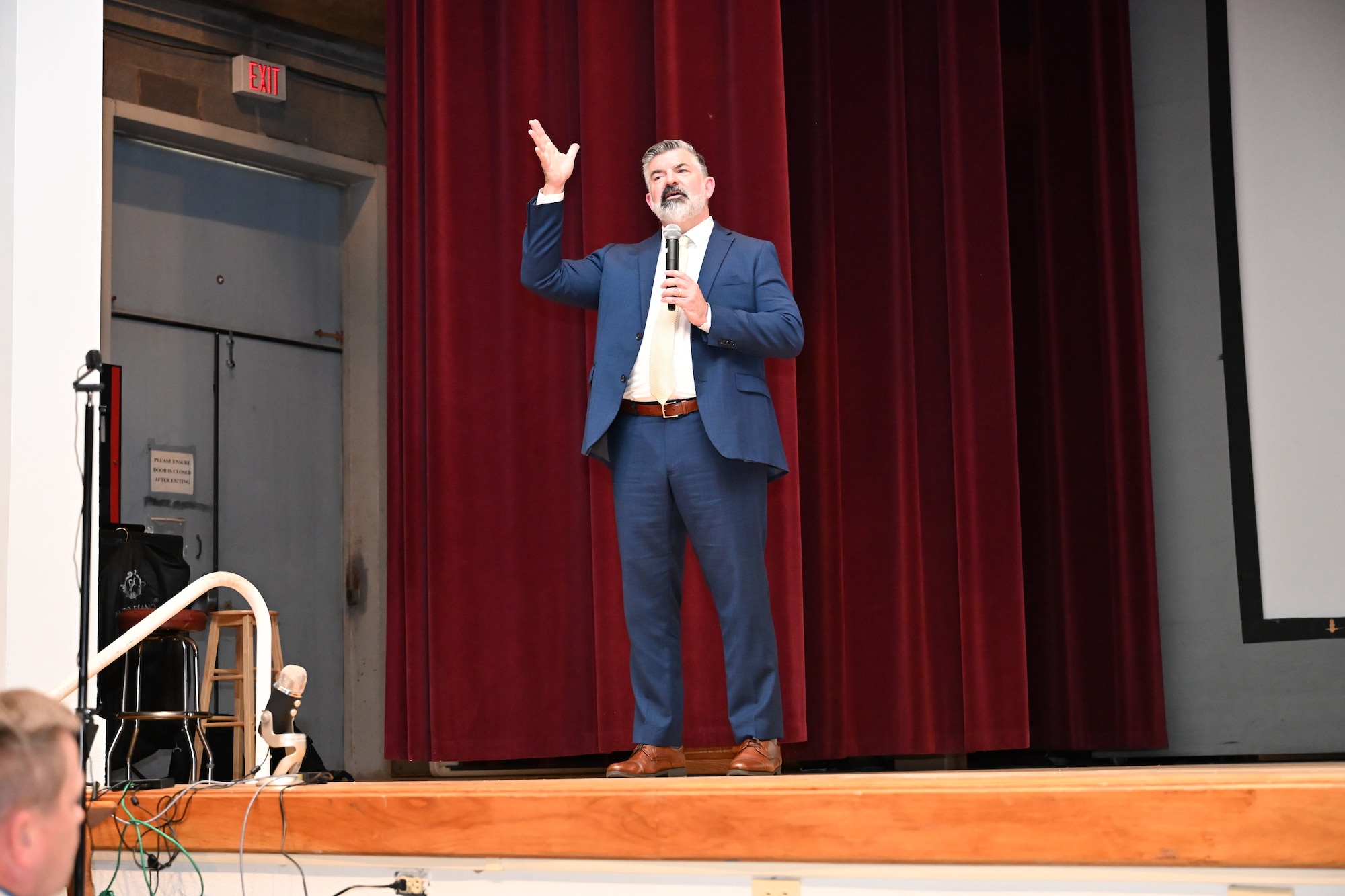 A man in a suit stands on a stage