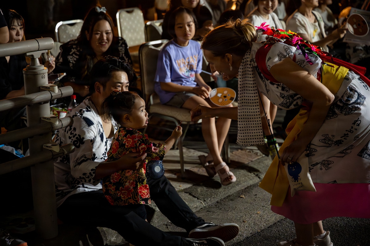 Robyn Lause, the 35th Fighter Wing commander’s spouse, gives a lucky bell to a child during a Nebuta Festival in Aomori City, Japan, Aug. 6, 2026. The exchange highlighted the community connections built through cultural participation, reinforcing the trust and people-to-people relationships that support the U.S.-Japan alliance. (U.S. Air Force photo by Senior Airman Andre Medina)