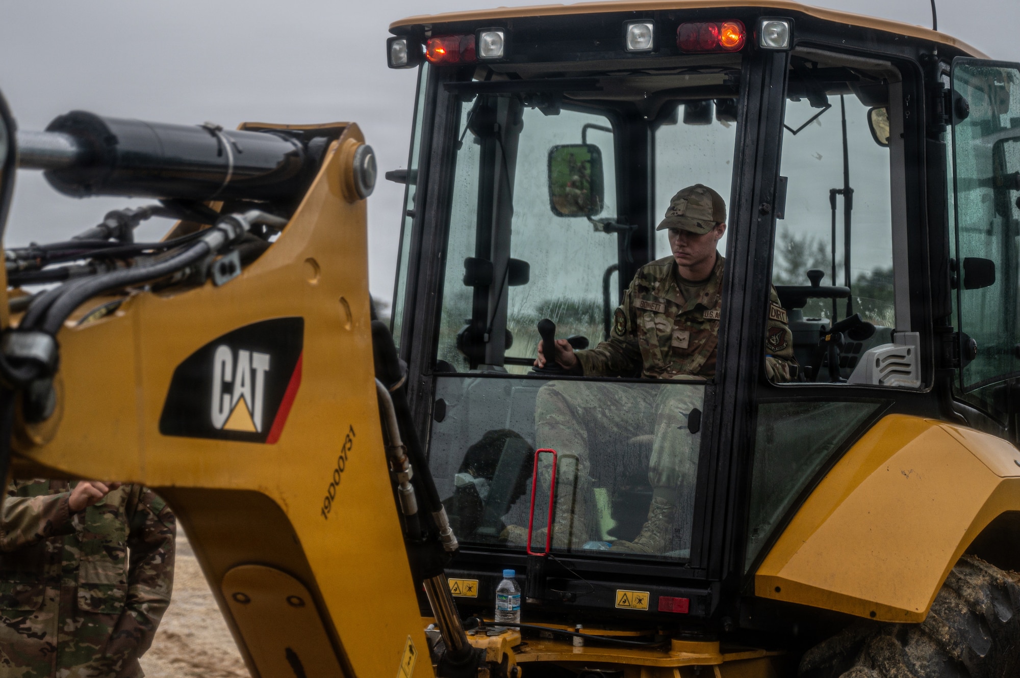 Airman operates an excavator during water line recovery.