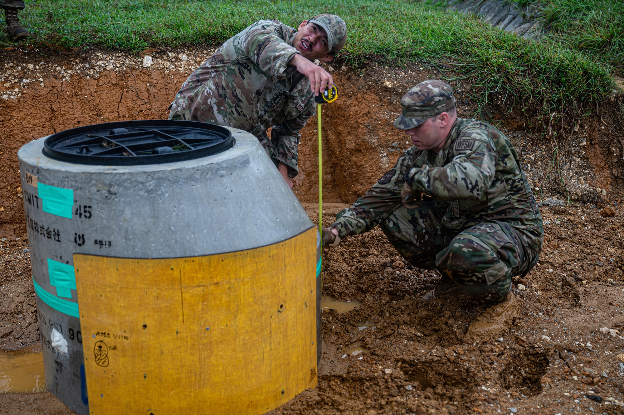 Airmen measure a manhole.