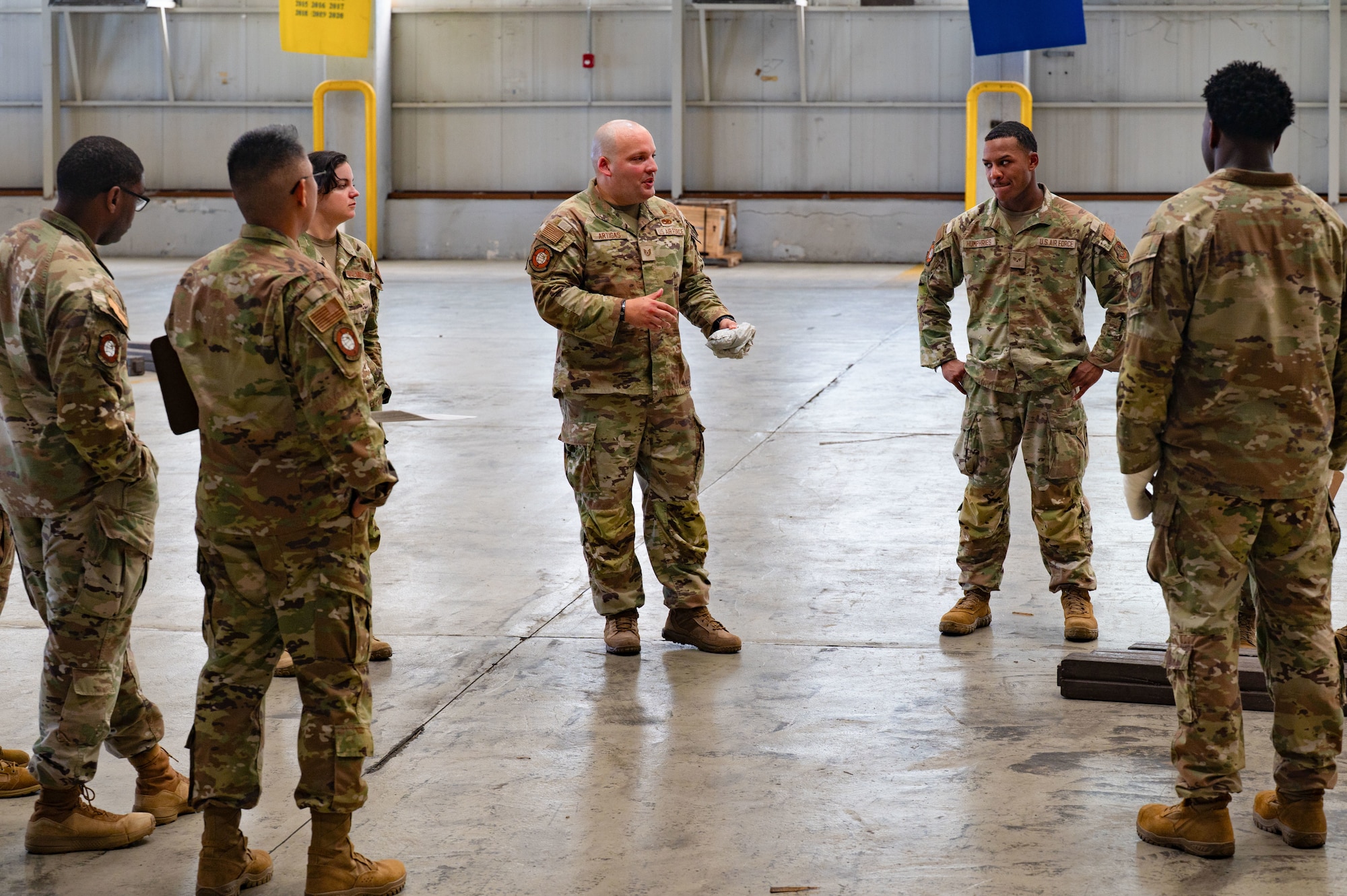 A group of airmen stand in a circle while one briefs to all the others.