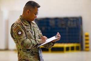 A man in uniform writes on a paper.