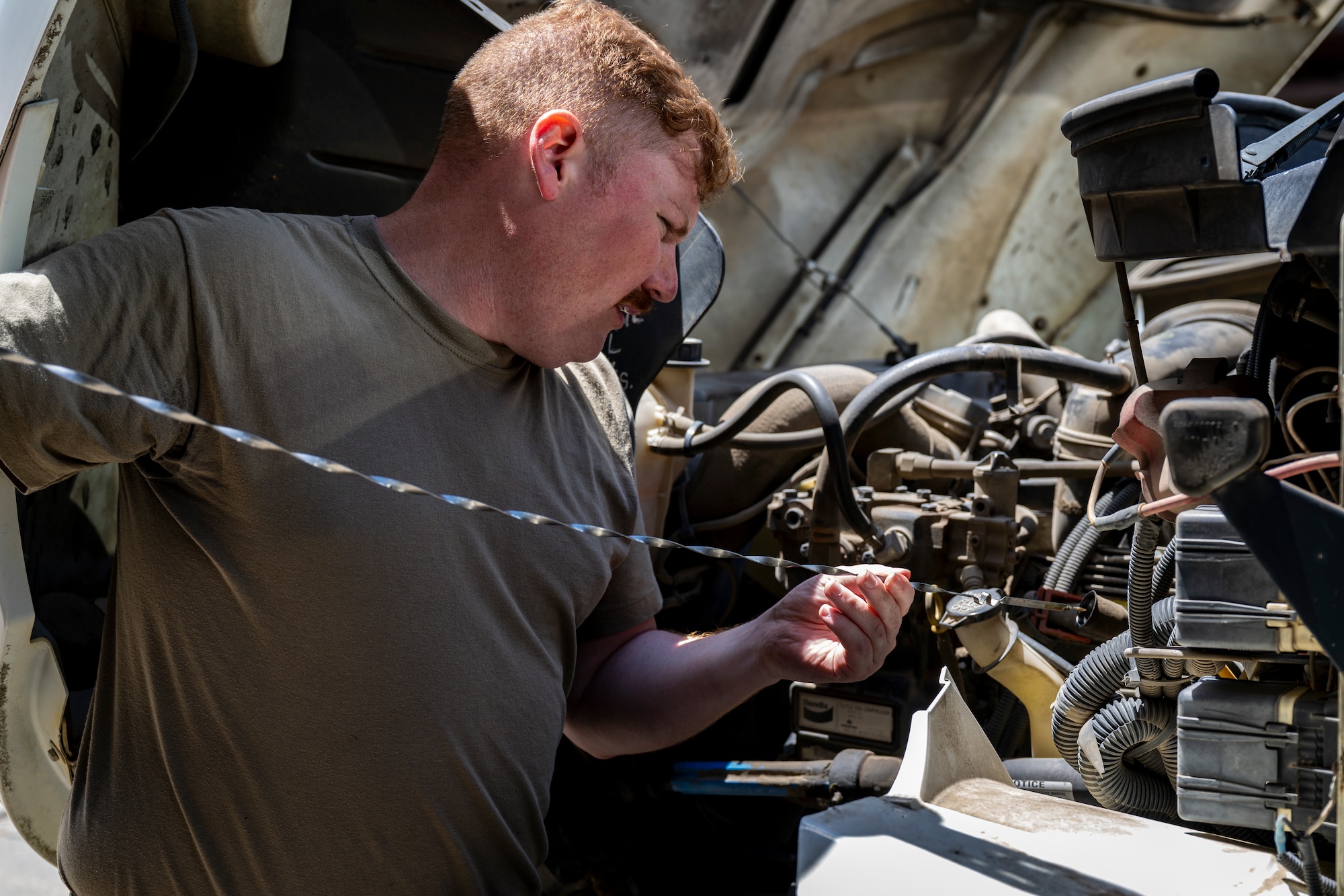 Vehicle Maintenance airman checking the oil of a vehicle