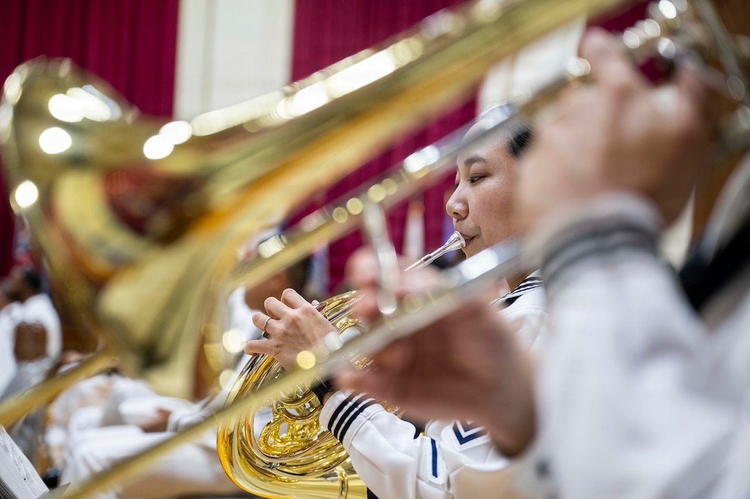 Seated sailors play brass instruments.