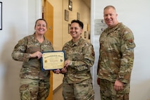 Col. Christine Littlejohn, Chief Master Sgt. Scott Castrovinci, and Tech. Sgt. Sarah Gonzales pose for a photo.