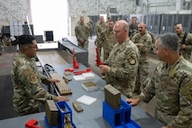 U.S. Air Force Tech. Sgt. Kelvin Moreno, 91st Missile Wing Atomic Spark innovation co-director, shows Gen. S.L. Davis, commander of Air Force Global Strike Command, and Chief Master Sgt. Shawn M. Aiello, command chief of AFGSC, a 3D-printed firearm magazine loader during a visit at Minot Air Force Base, North Dakota, July 30, 2026.