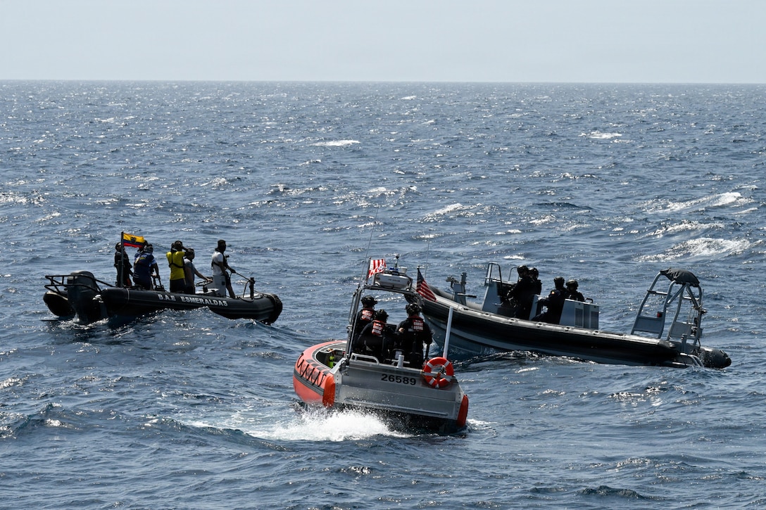 Three small boats, each with crews of a few people, converge near one another in a large body of water during daytime.