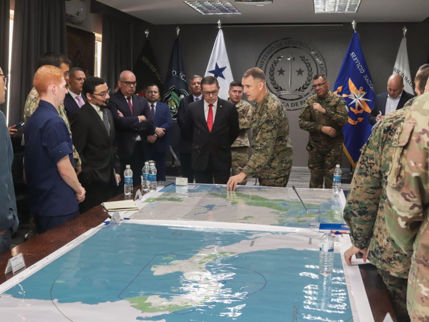 A group of U.S. and Panamanian government officials gather around a table and look at a map of Panama