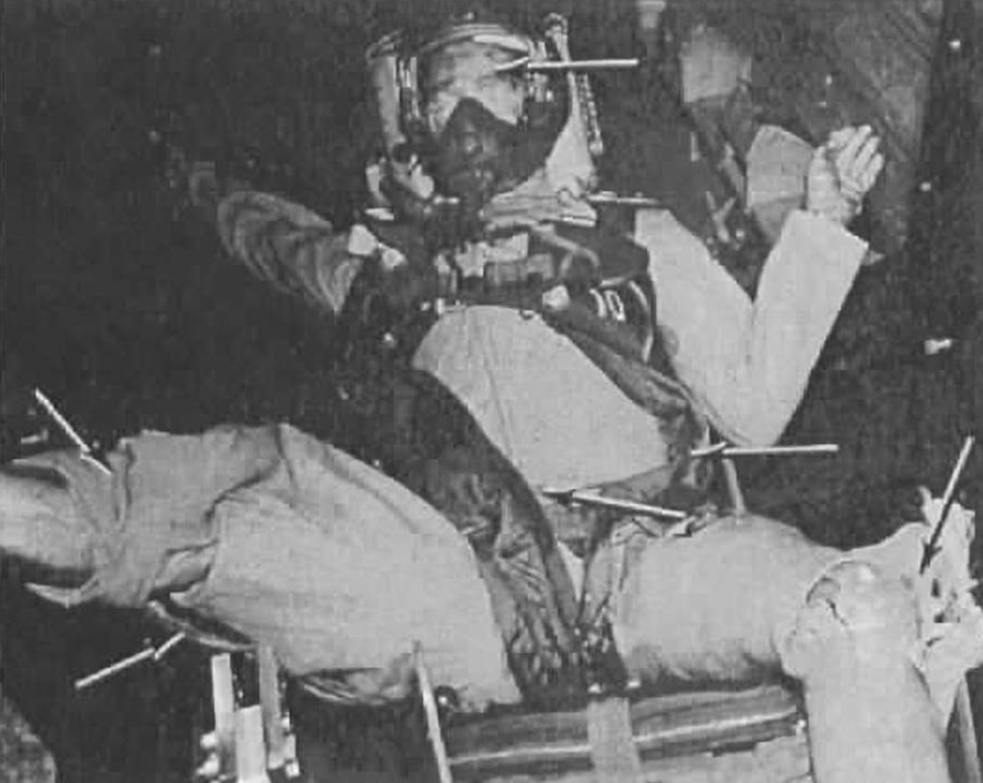 The damage done to a dummy following wind blast testing in the T-2 test cell of the Arnold Engineering Development Center Engine Test Facility is highlighted is this photo from a 1957 technical report. Arrows where pressure from the blast either damaged or resulted in movement of the dummy or equipment. This testing, conducted in June 1957, assessed the impact of dynamic pressure on several configurations of flight gear. (U.S. Air Force image)