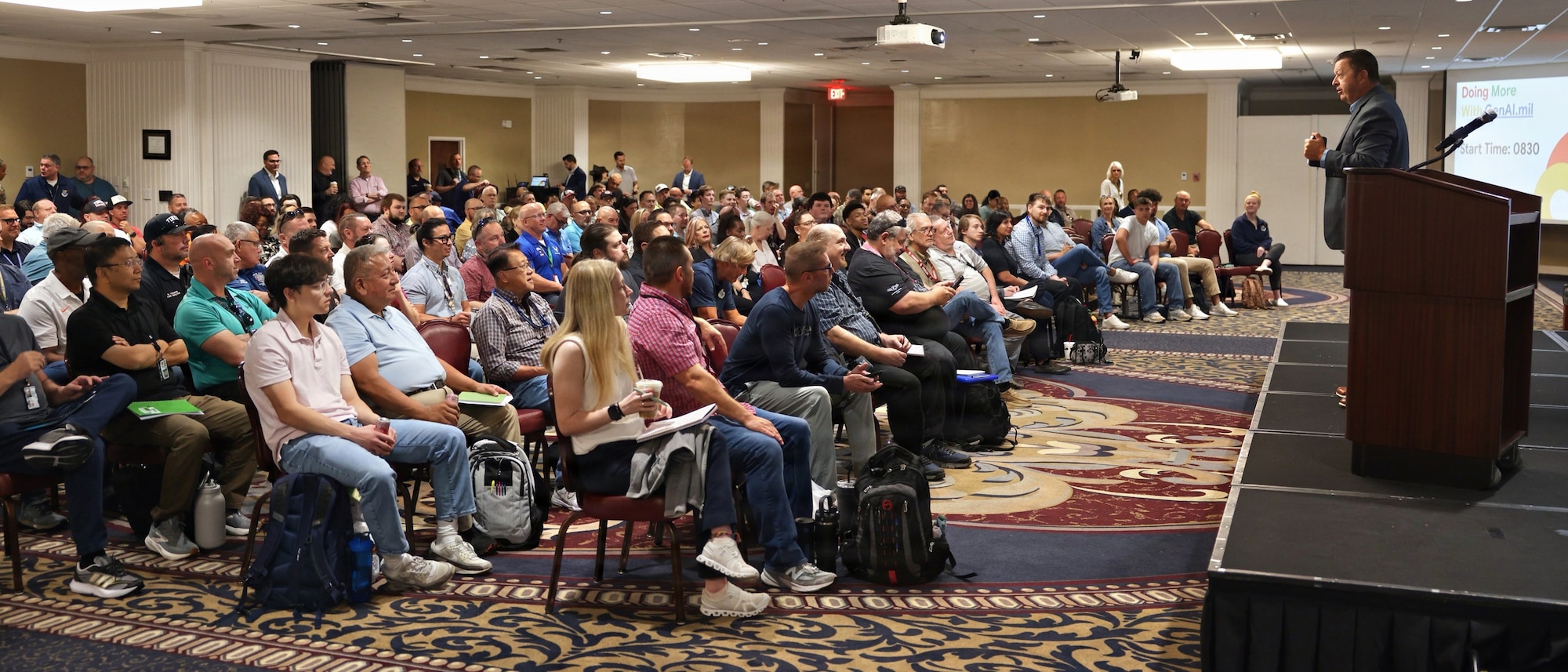 A man on stage speaks to an audience.