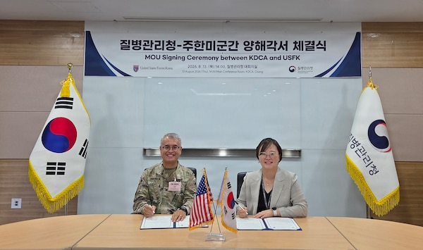 Col. Eric Swanson and a Korea Disease Control and Prevention Agency official sit at a table signing a Memorandum of Understanding during the 2026 SOFA Subcommittee on Disease Prevention and Control in Osong.