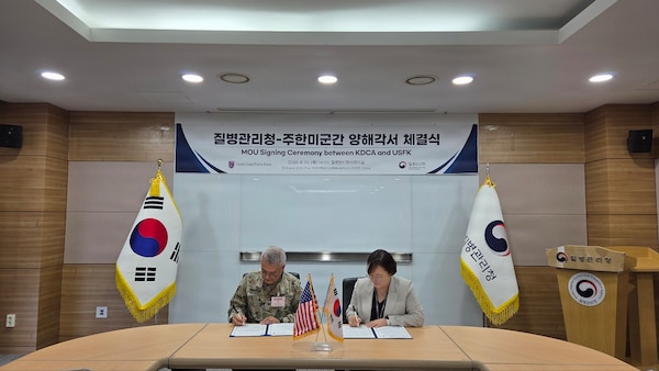 Col. Eric Swanson and a Korea Disease Control and Prevention Agency official sit at a table signing a Memorandum of Understanding during the 2026 SOFA Subcommittee on Disease Prevention and Control in Osong.