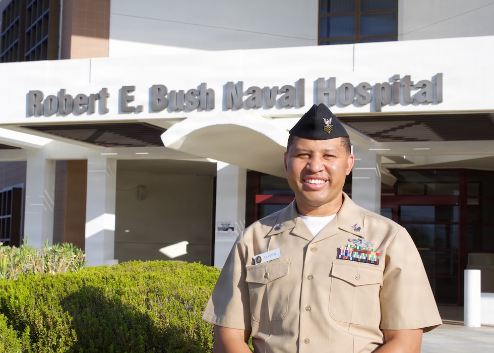 Hospital Corpsman 1st Class Raphael R. Claxton, senior enlisted leader for the Directorate for Public Health at Naval Hospital Twentynine Palms, operated by Navy Medicine Readiness and Training Command Twentynine Palms, and senior preventive medicine technician for the Expeditionary Medical Facility Bravo detachment at Twentynine Palms, stands in front of Robert E. Bush Naval Hospital, Aug. 7, 2026. Claxton was selected as EMF Bravo’s Senior Sailor of the Quarter for his leadership and efforts to strengthen preventive medicine, force health protection and operational readiness. (U.S. Navy photo by Hospital Corpsman 3rd Class Evelyn Zermeno.)