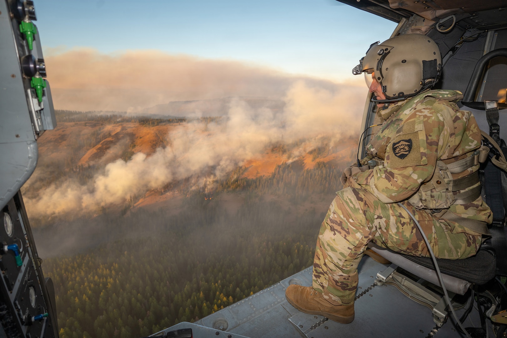 U.S. Army Staff Sgt. Kyle Sanders, a crew chief with G Company, 1st Battalion, 189th Aviation, looks out over the Hagen Fire's burn scar in Umatilla County, Oregon, as an HH-60M Black Hawk helicopter returns to Army Aviation Support Facility #2 in Pendleton, Aug. 10, 2026.
