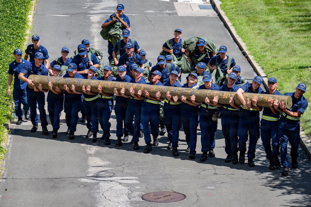 U.S. Coast Guard cadets work together to carry a log uphill during Sea Trials at the Academy in New London, Conn., Aug. 14, 2026. The daylong event tests swabs physical endurance, mental resilience and teamwork as they complete their summer training program. (U.S. Coast Guard photo by Petty Officer 3rd Class Roxanna Jacobo Cruz.)