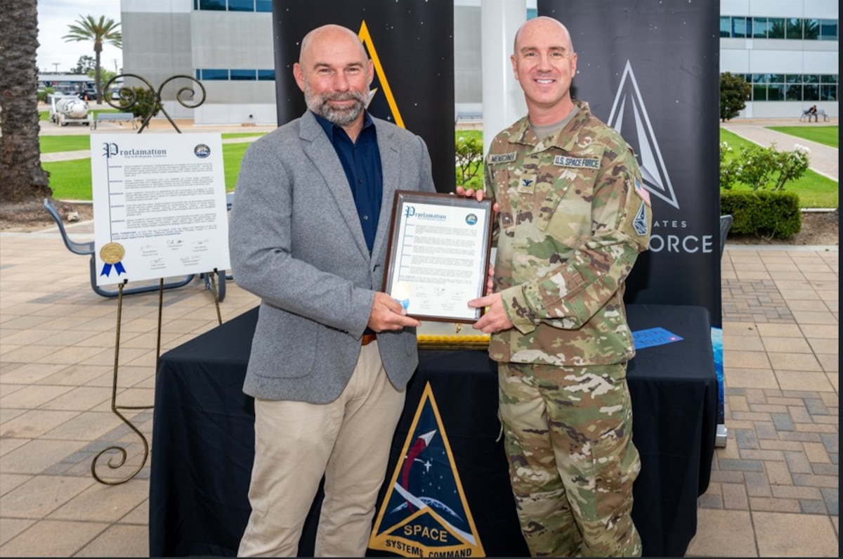 From left, Chris Pimentel, Mayor of El Segundo, Calif., presents a proclamation to USSF Col. Andrew Menschner, deputy commander, Space Systems Command (SSC), at Los Angeles Air Force Base in El Segundo, Calif. to commemorate the 5th anniversary of SSC’s stand up as a U.S. Space Force Field Command on Aug. 13, 2026. SSC is the Nation’s premier space acquisition organization responsible for fielding space-based capabilities that protect our Nation’s interests in, from and to space. SSC is headquartered at LA AFB with operating locations throughout the country including space launch operations at Cape Canaveral Space Force Station and Patrick Space Force Base in Fla. and Vandenberg Space Force Base in Calif. (U.S. Space Force photo by Chris Kim)