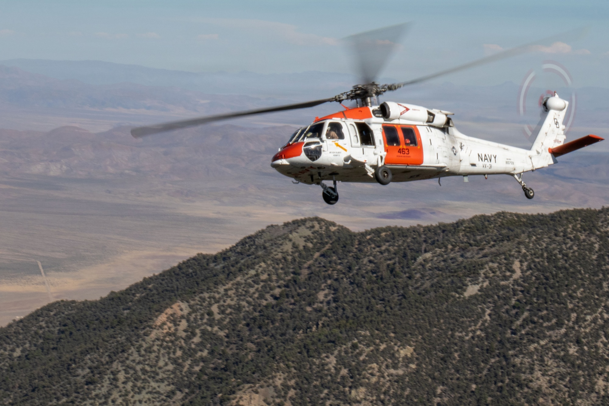 An Air Test and Evaluation Squadron (VX) 31 MH-60S Seahawk flies over mountainous terrain during search and rescue training at Naval Air Weapons Station China Lake, California, June 15, 2026. VX-31's search and rescue crews train across desert and mountain terrain to sustain readiness for the squadron's developmental flight test mission. (U.S. Navy photo by Michael L. Smith)