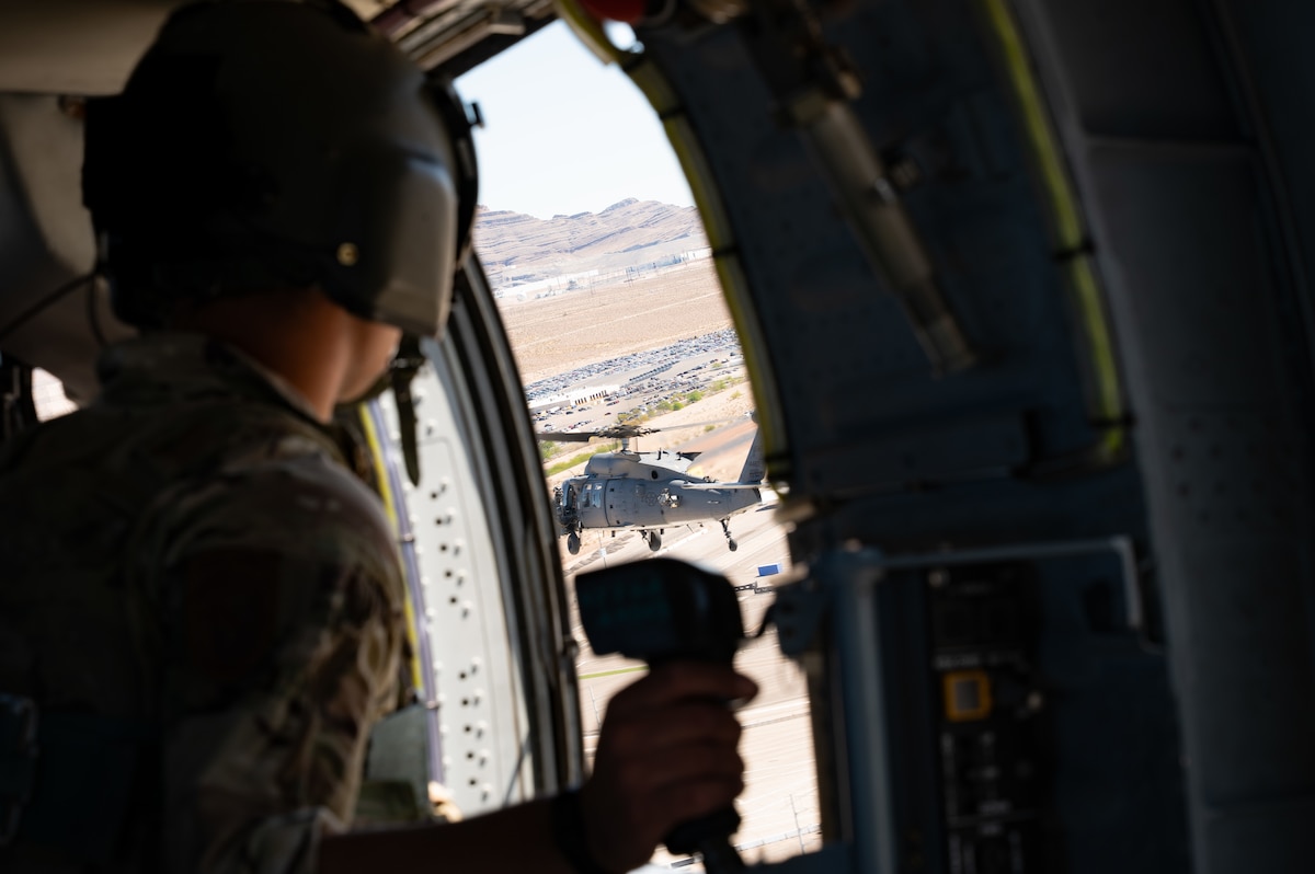 U.S. Air Force Staff Sgt. Devon Curtis, a special missions aviator assigned to Detachment 1, 413th Flight Test Squadron, looks at an HH-60W Jolly Green II assigned to the 88th Test and Evaluation Squadron while flying above Nellis Air Force Base, Nevada, April 29, 2025. Recently on Aug. 10, 2026, the 88 TES rapidly generated and deployed two HH-60W Jolly Green II helicopters to rescue five U.S. Navy personnel following an aircraft mishap near Naval Air Weapons Station China Lake, California. (U.S. Air Force photo by Staff Sgt. Jose Miguel T. Tamondong)