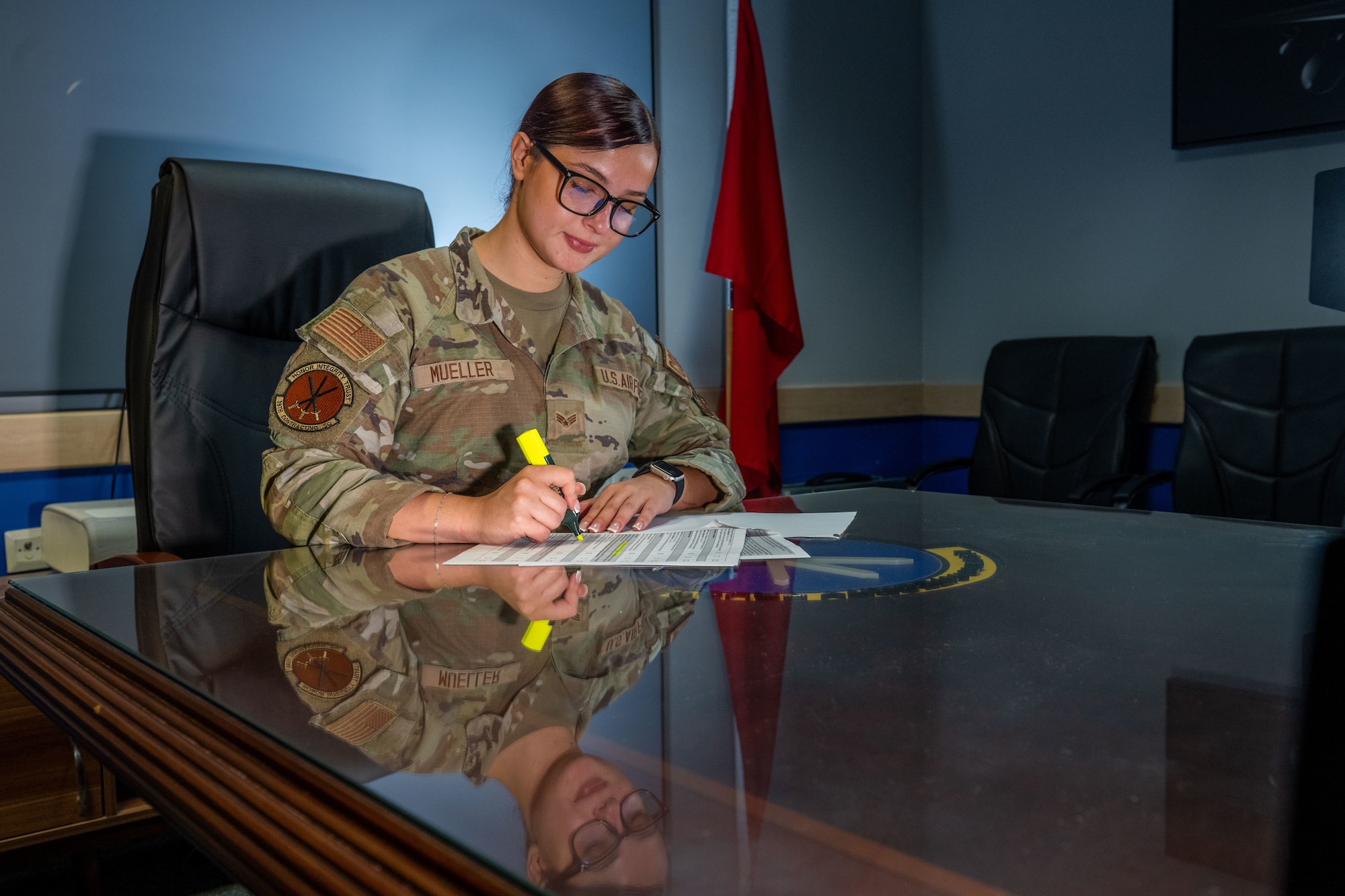 A woman in uniform highlights at a desk.