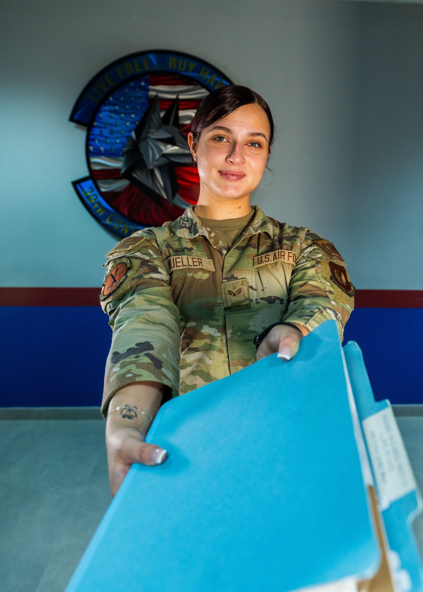 A woman in uniform hands a folder to someone off camera.
