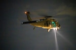 An Alabama Army National Guard UH-60 Black Hawk helicopter conducts nighttime medical evacuation training during Operation Tuskegee Thunder at Dannelly Field, Alabama, Aug. 13, 2026. The aircraft’s searchlight illuminated the training area as ground personnel and aircrew practiced coordinated evacuation operations. Photo by Master Sgt. William Blankenship.