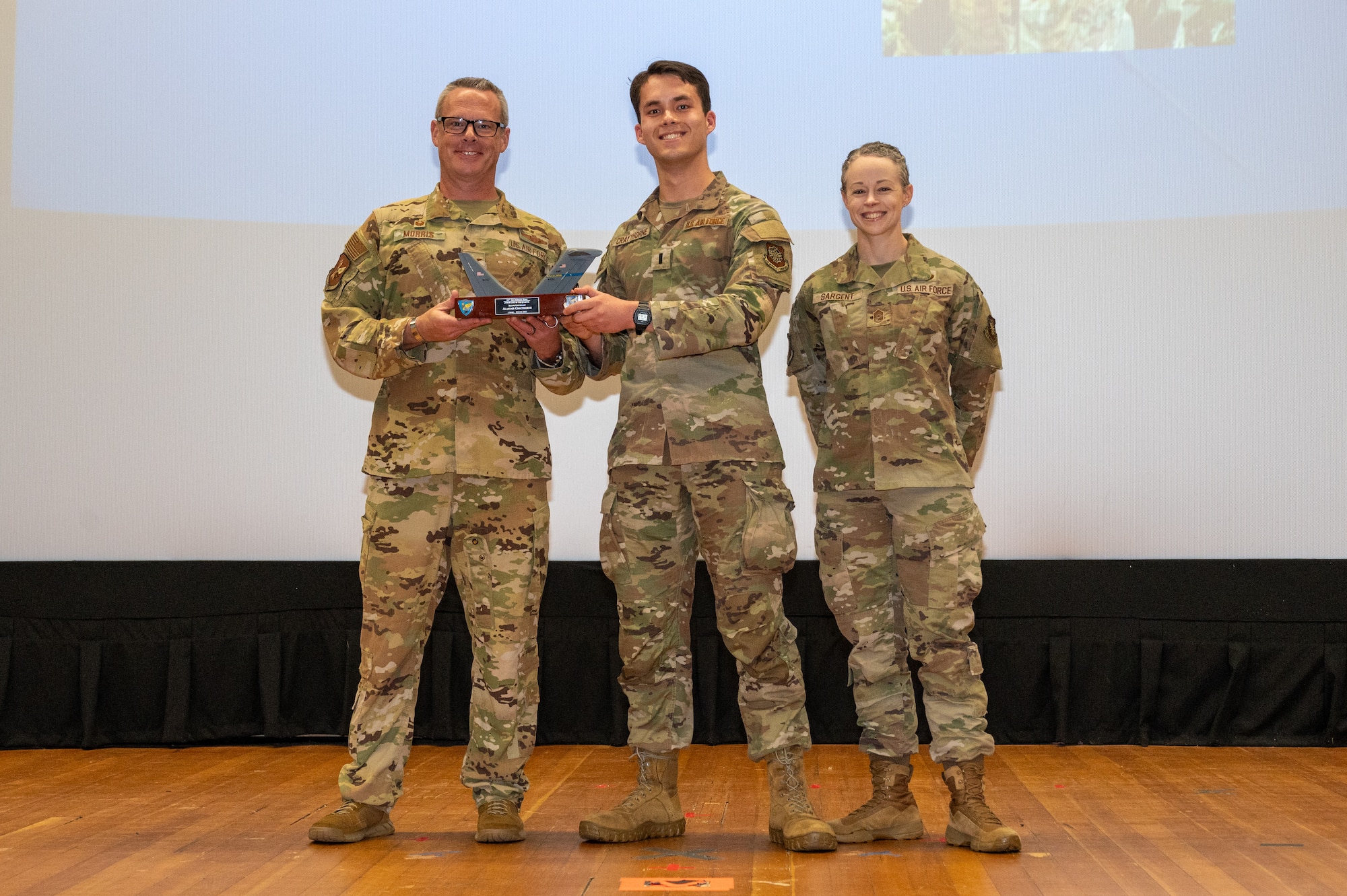 U.S. Air Force Col. Allen Morris, left, 305th Air Mobility Wing commander, and Chief Master Sgt. Tiffany Sargent, right, 305th AMW command chief, present 1st Lt. Alastair Craythorne, 305th Arial Port Squadron assistant director of operations, an award at Joint Base McGuire-Dix-Lakehurst, N.J., Aug. 10, 2026.