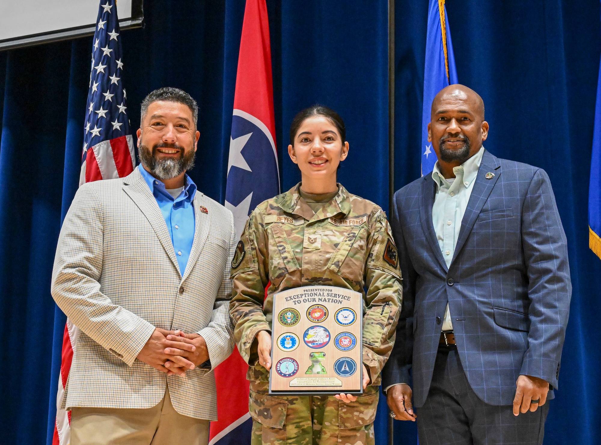 U.S. Air Force Tech. Sgt. Andrea Reyes, center, an instructor with the Chief Master Sgt. Paul H. Lankford Enlisted Professional Military Education Center, I.G. Brown Training and Education Center, receives the GEICO Military Service Award from Chino Levia, left, and Ed Sizer, right, members of the GEICO Military Affairs Team, at McGhee Tyson Air National Guard Base, Tennessee, June 15, 2026. Reyes was selected from nominees representing the Army National Guard and Air National Guard across the country for her contributions to Airmen, her unit, and her community. (U.S. Air National Guard photo by Master Sgt. Regina Young)