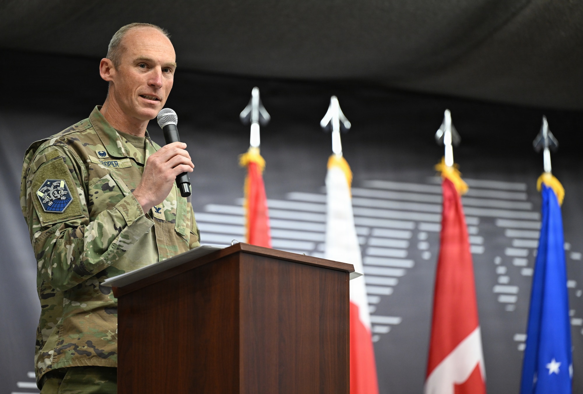 Col. Charles Cooper speaks from behind a podium.