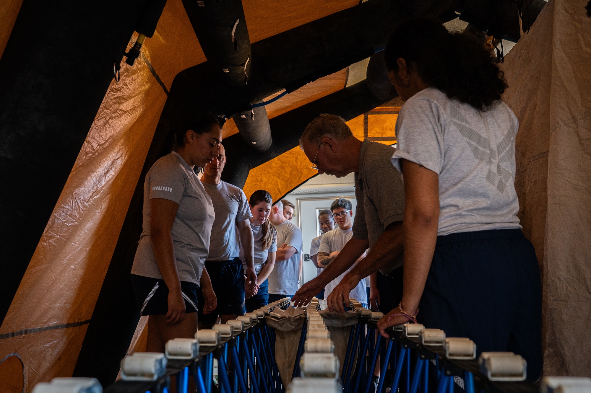 A photo of a man speaking to a group of people while standing in medical tent.