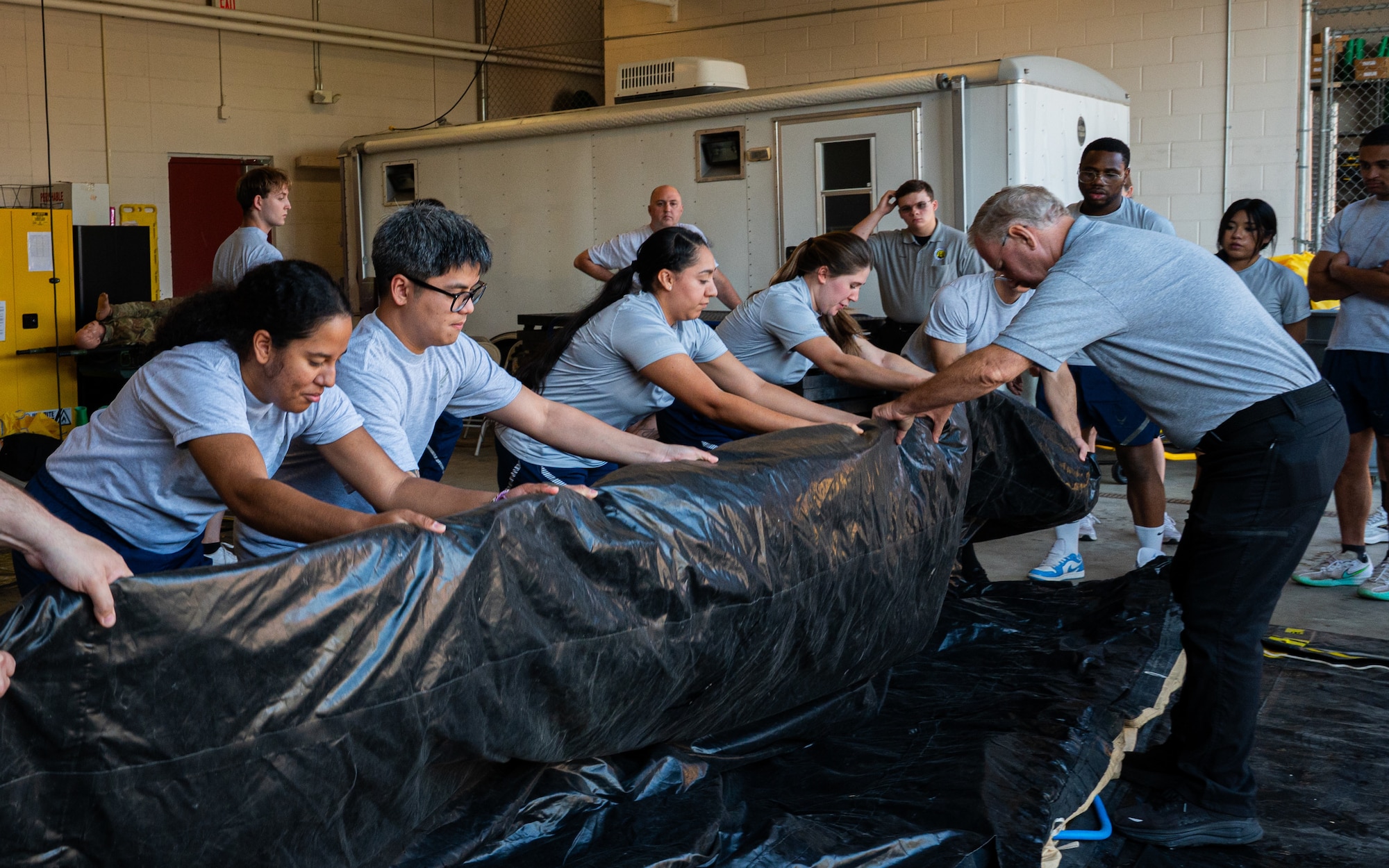 A photo of a group of people folding a black tarp.