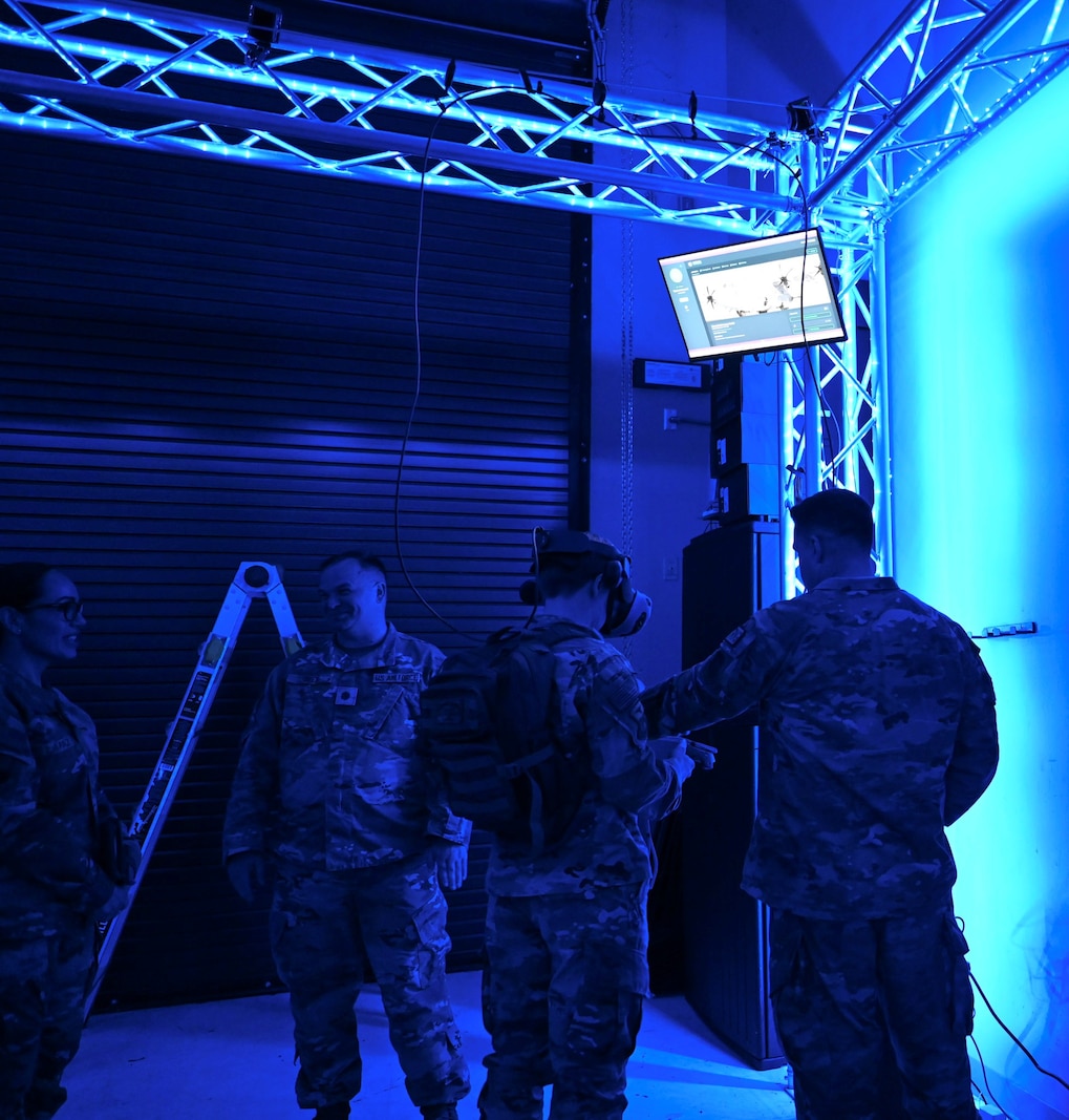 A man is wearing a virtual reality mask while standing in a room lit with blue lighting.