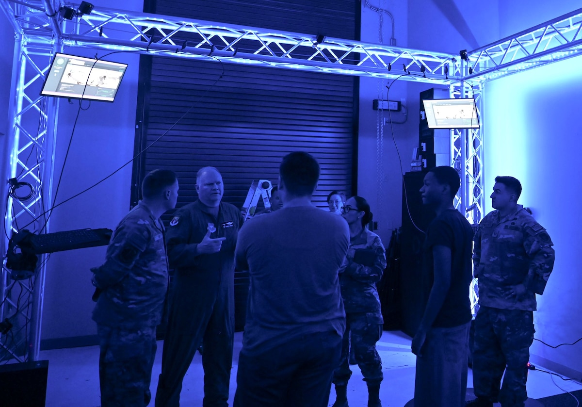 A group of people stand in a room lit with blue light talking.