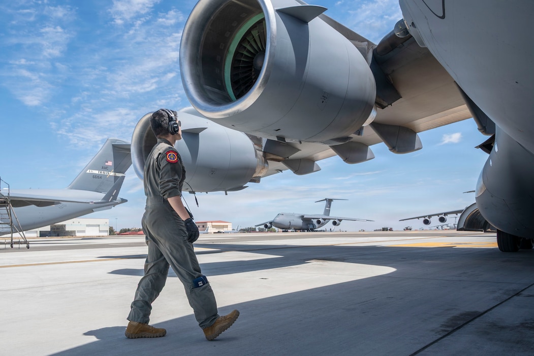 A pilot walking under the wing of an aircraft.