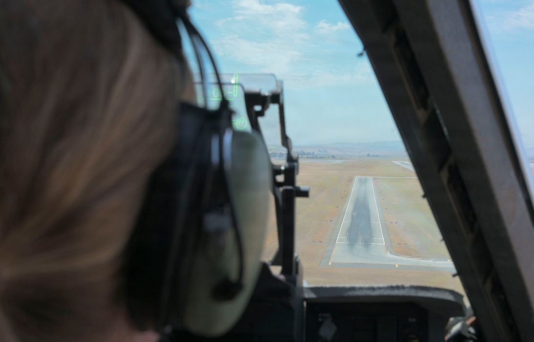 A runway through an airplane windshield from above the ground.