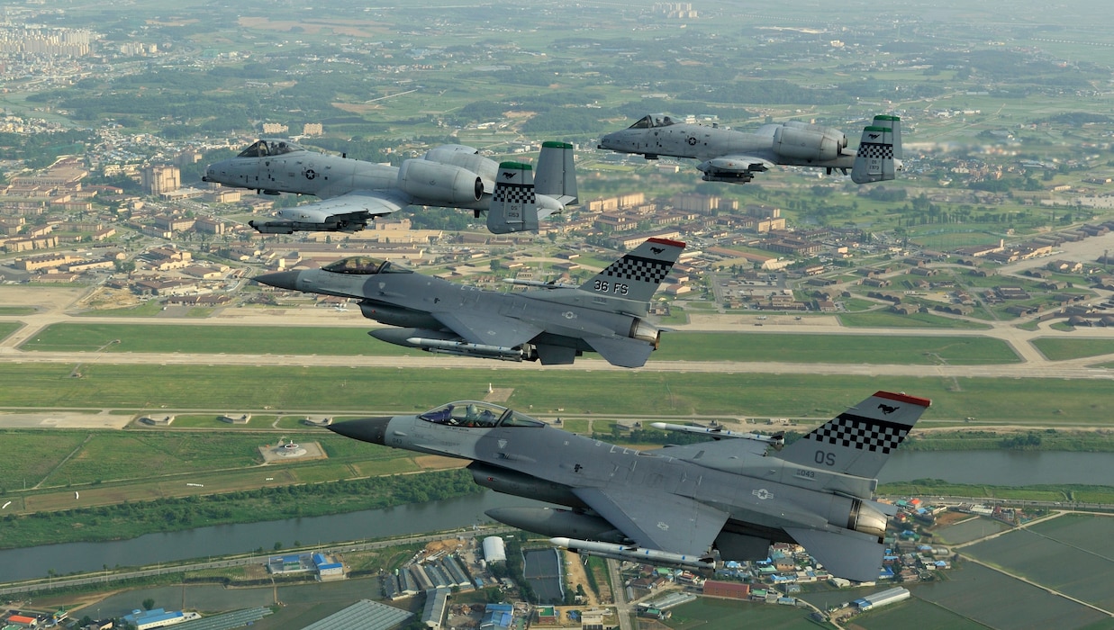 Two F-16 Fighting Falcons from the 36th Fighter Squadron fly alongside two A-10 Thunderbolt IIs from the 25th Fighter Squadron during a four-ship "checkertail" flyover of Osan Air Base, South Korea, circa 2009. This mixed-fleet pairing served as the cornerstone of the peninsula's air defense for decades.