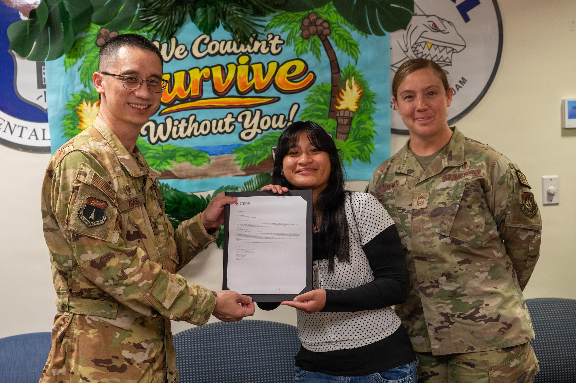 U.S. Air Force Col. Joe Zhang, 36th Medical Group commander, left, and U.S. Air Force Chief Master Sgt. Amanda Evachek, right, 36th Medical Group senior enlisted leader, present a certificate of appreciation to Sofia Labus, center, American Red Cross VolunTEEN, during the American Red Cross VolunTEEN closing ceremony at Andersen Air Force Base, Guam, Aug. 13, 2026. The ceremony celebrated the six weeks of service participants dedicated to the 36th MDG and the Andersen community throughout the summer. (U.S. Air Force photo by Airman 1st Class Charline Ebreo)