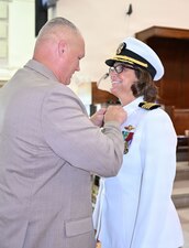 Capt. Cindi Palacios, incoming Naval Hospital (NH) Jacksonville director and Navy Medicine Readiness and Training Command Jacksonville commander, has her command pin placed on her uniform by her husband Eric during the change of command ceremony, Aug. 13. This time-honored Navy tradition saw Capt. Craig Malloy turn over leadership of NH Jacksonville, comprised of the Navy’s third largest hospital and five branch health clinics across Florida and Georgia. (U.S. Navy photo by Julie M. Lucas, Naval Hospital Jacksonville Public Affairs/released)