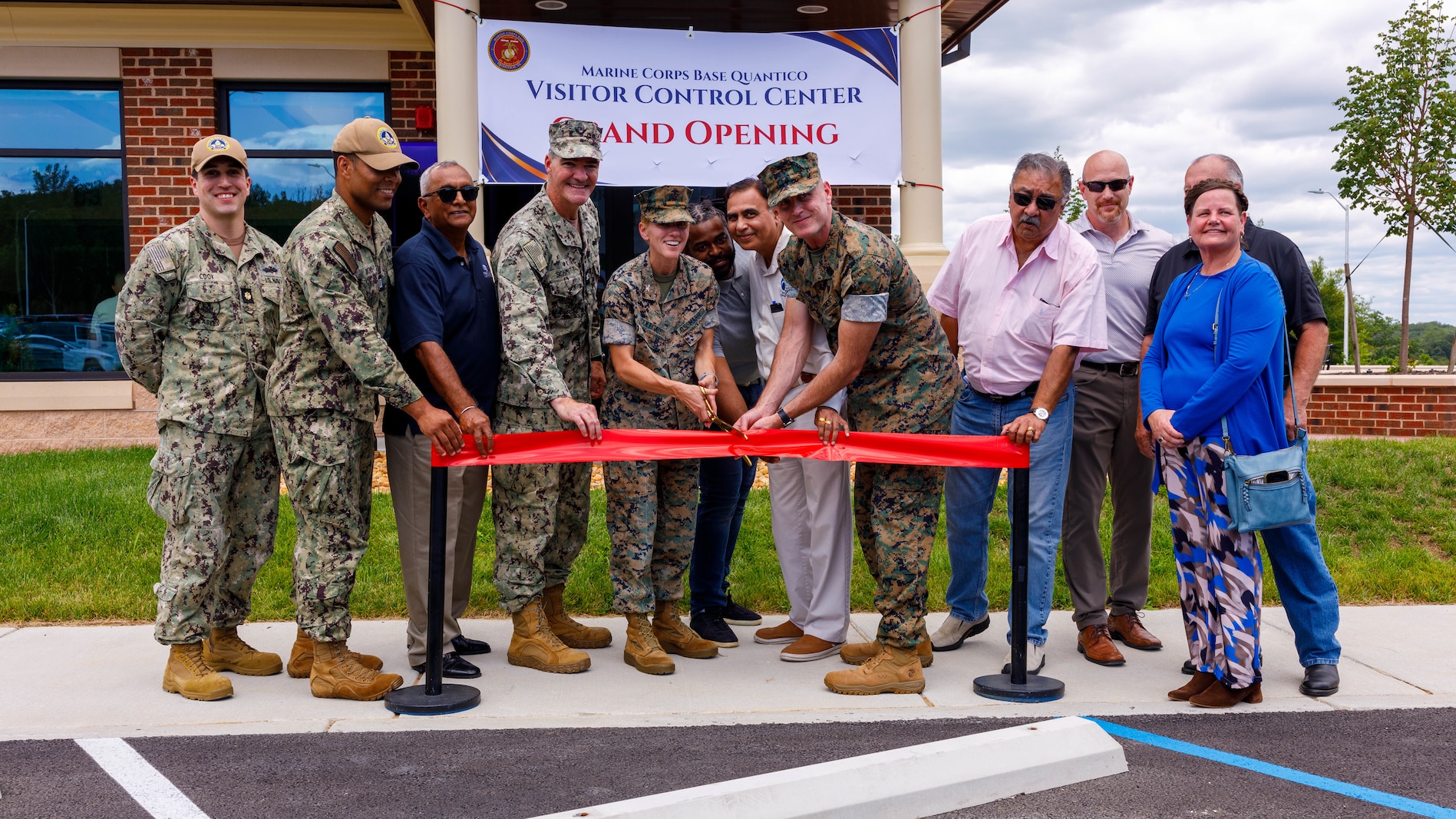 U.S. service members, sponsors, engineers, and contractors conduct the cutting of the ribbon during the grand opening of the new Visitor Control Center of Marine Corps Base Quantico, Virginia, July 30, 2026. The VCC supports installation security by verifying the identity and eligibility of non-Department of War personnel, contractors, and other authorized guests. (U.S. Marine Corps photo by Lance Cpl. Lynsee Avila-Ramirez)