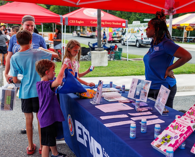 Community members interact with a vendor’s booth during National Night Out at the Crossroads Elementary School on Marine Corps Base Quantico, Virginia, Aug. 4, 2026. National Night Out is an annual community-building campaign that enhances the relationships between law enforcement, first and emergency responders with members of the local community. (U.S. Marine Corps photo by Lance Cpl. Donavan E. Melendez)